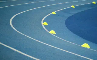 A curved blue running track marked with white lane lines